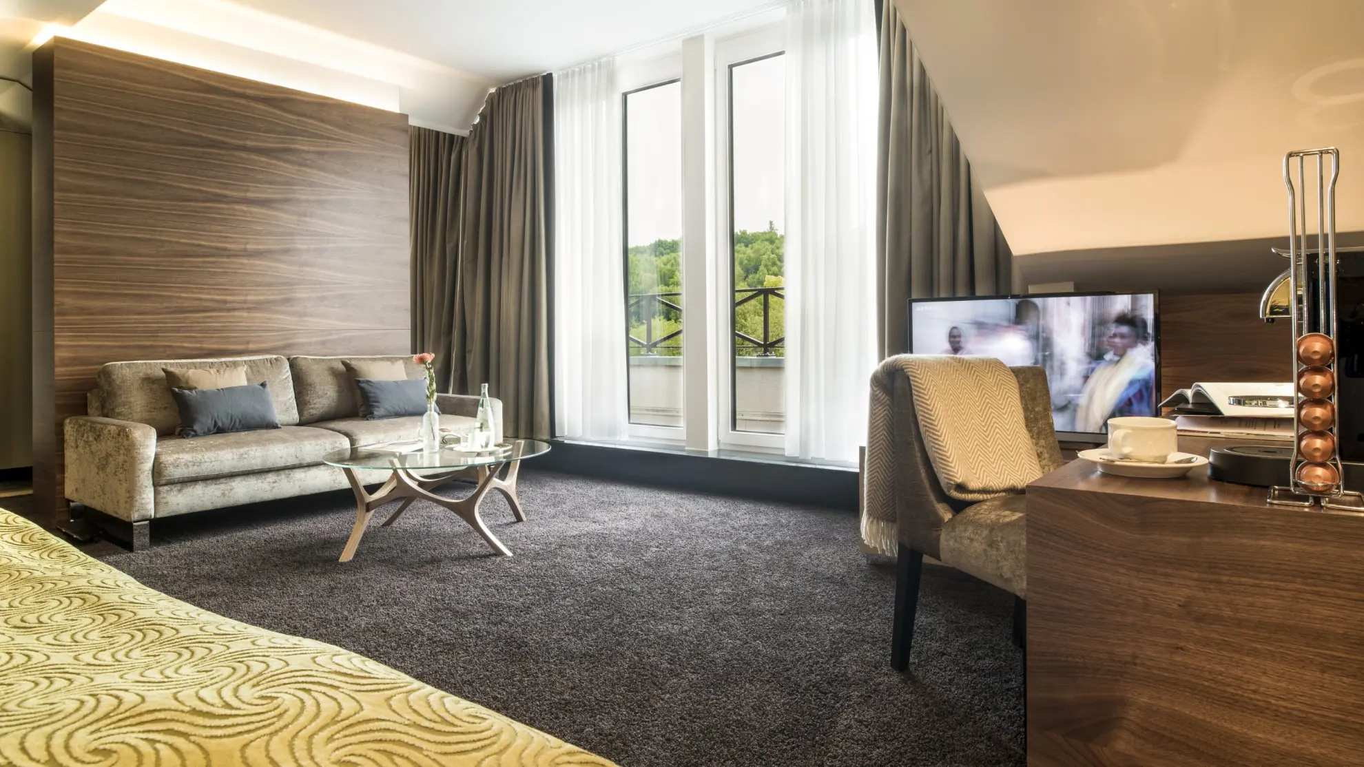 Juniorsuite mit Dachschraege Couch Schreibtisch Doppelbett und gruener Tagesdecke