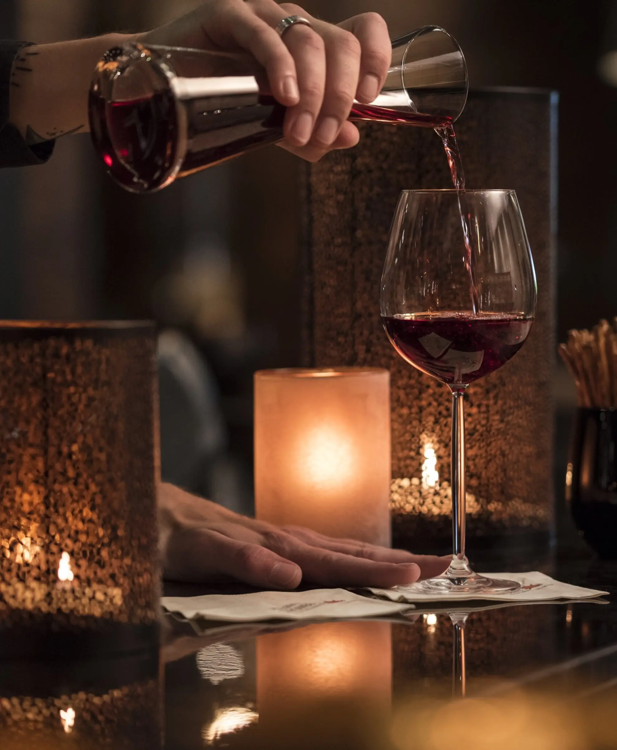 Hotelbar Birdie in Abendstimmung beleuchtet Barkeeper giesst Rotwein in ein Burgunderglas