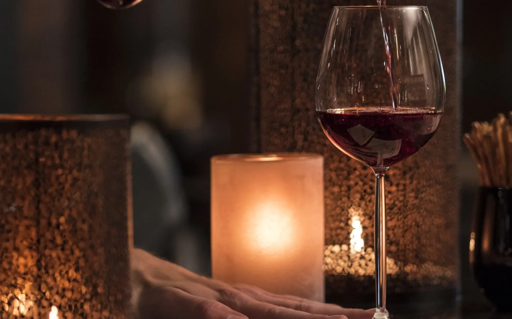 Hotelbar Birdie in Abendstimmung beleuchtet Barkeeper giesst Rotwein in ein Burgunderglas
