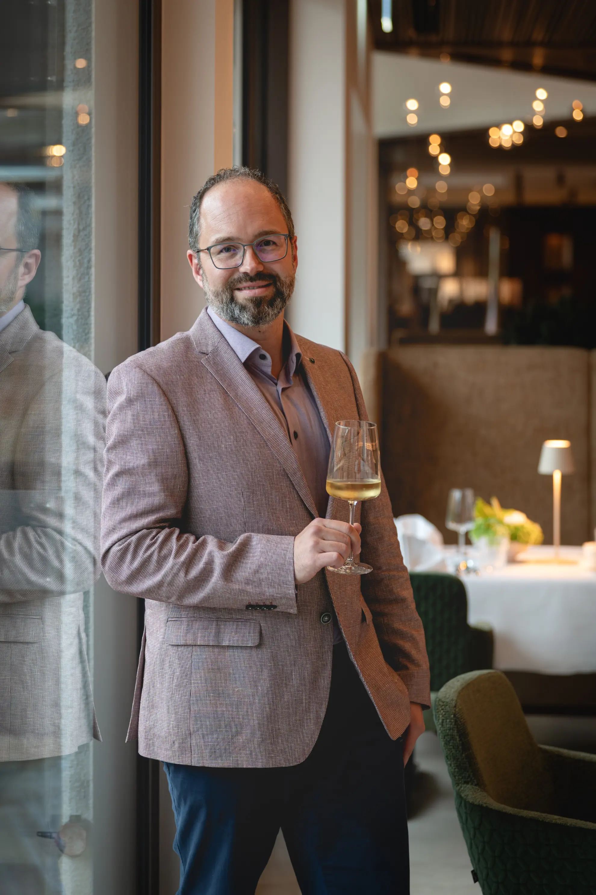 Garten Restaurant Marcus Beetz Direktor im Anzug steht mit Weinglas im Restaurant