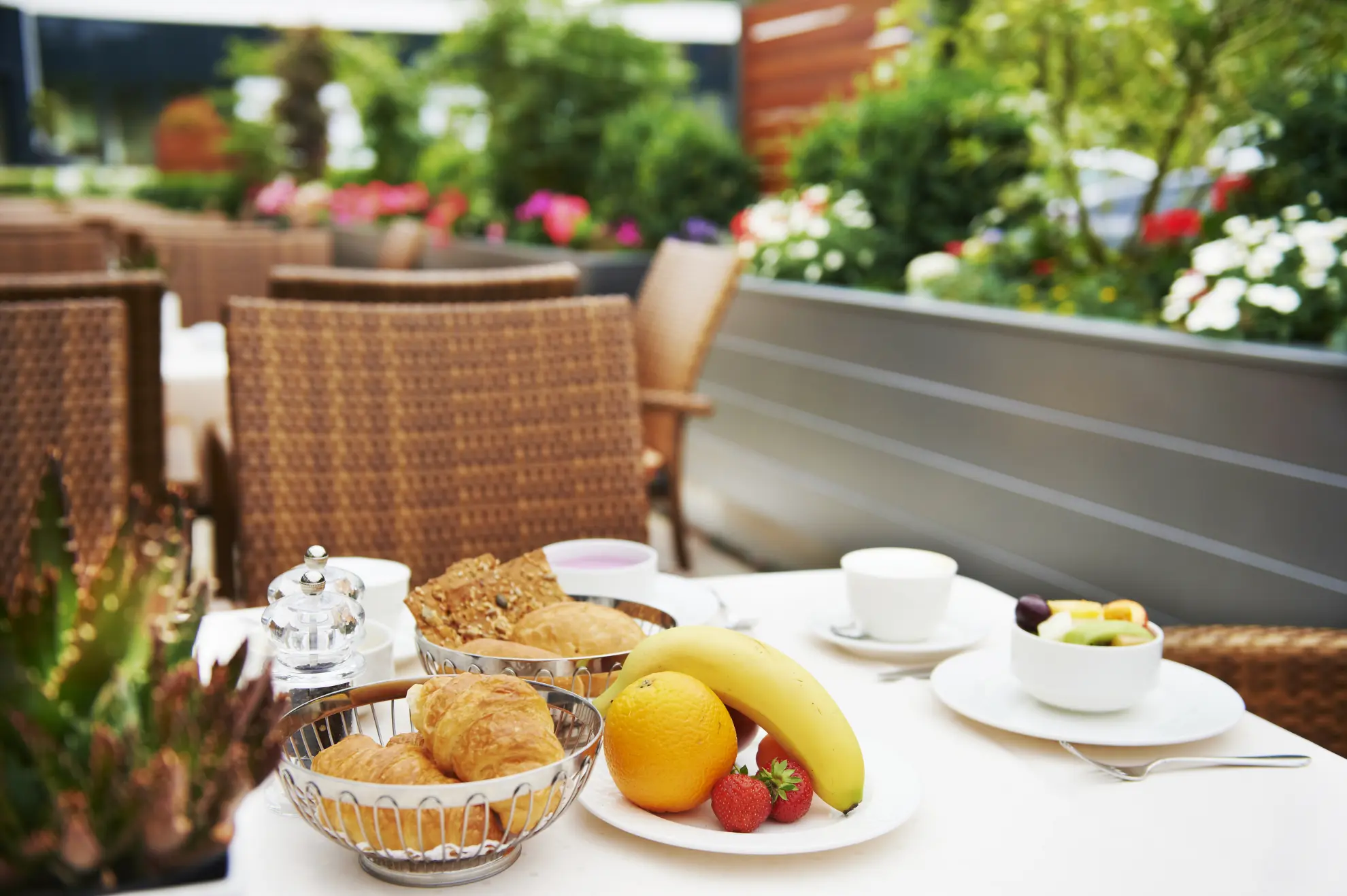 Sommertrrasse Fruehstueck mit Kaffee Croissants Broetchen und Obst