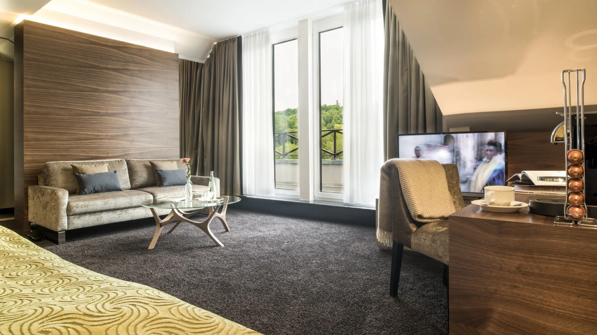 Juniorsuite mit Dachschraege Couch Schreibtisch Doppelbett und gruener Tagesdecke