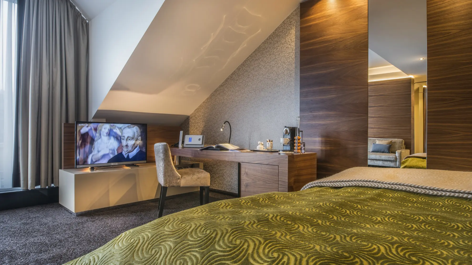 Juniorsuite mit Dachschraege Doppelbett und gruener Tagesdecke