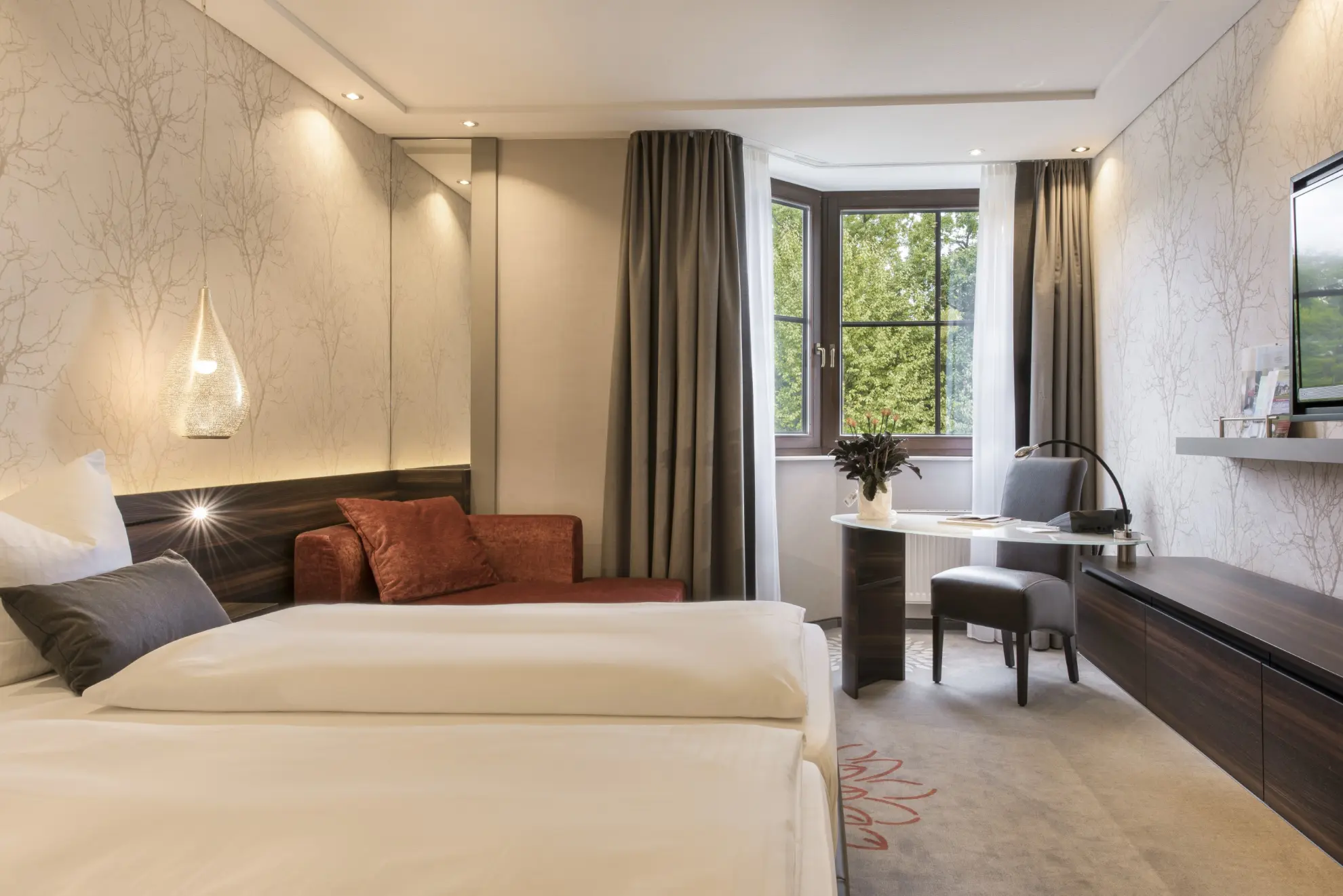 Komfort Doppelzimmer mit Doppelbett  heller Tapete mit Zweigen Sideboard TV und Schreibtisch