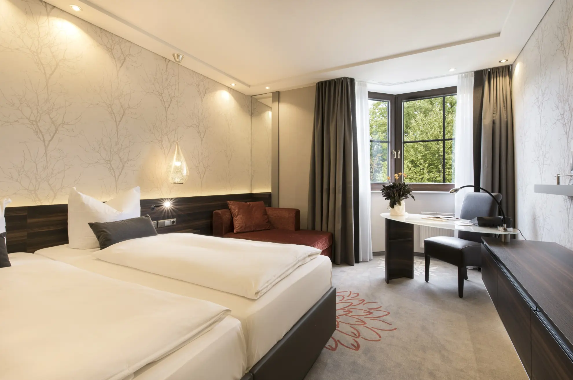 Komfort Doppelzimmer mit Doppelbett  heller Tapete mit Zweigen Sideboard TV und Schreibtisch 1