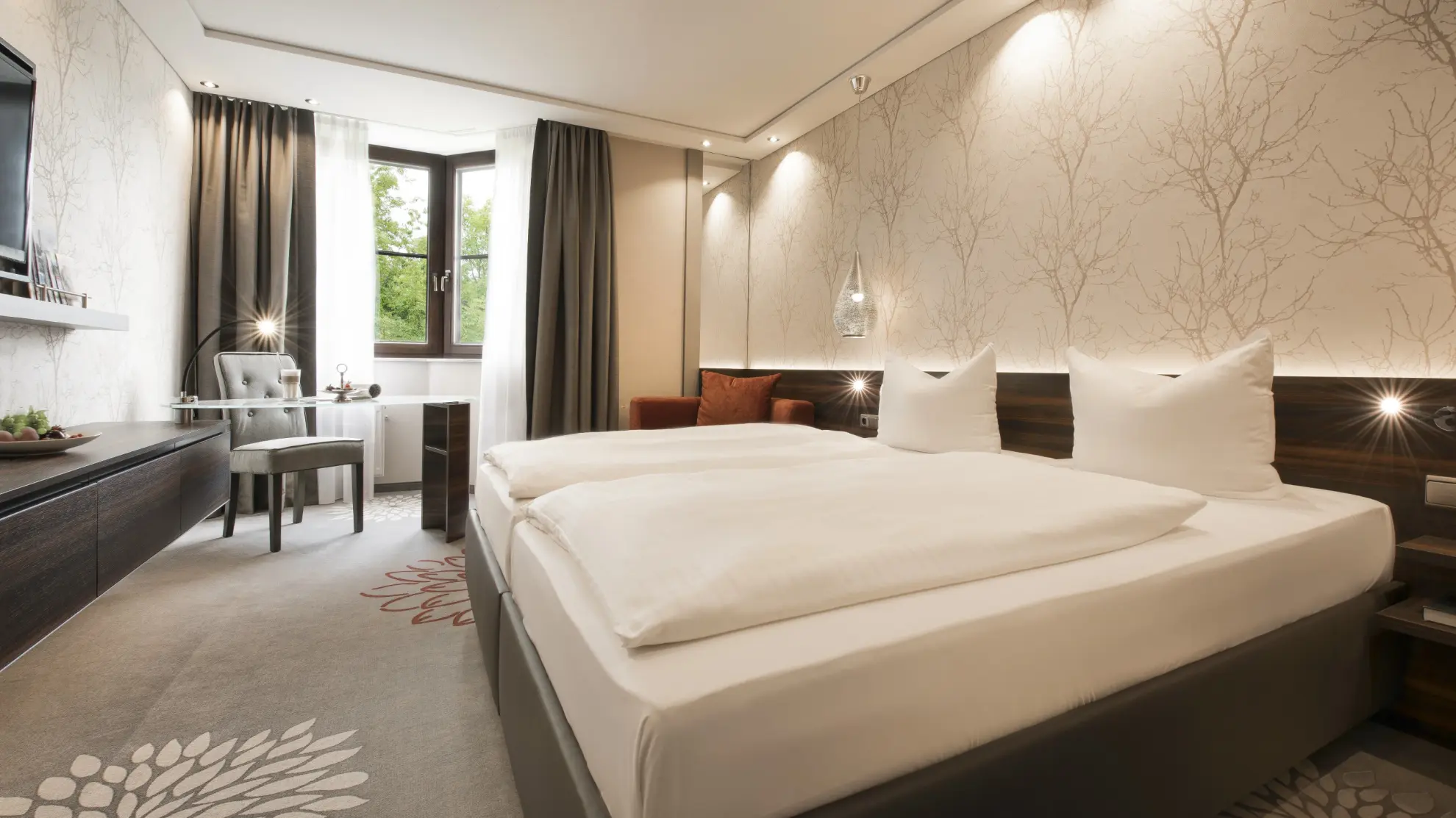 Komfort Doppelzimmer mit Doppelbett und heller Tapete mit Zweigen