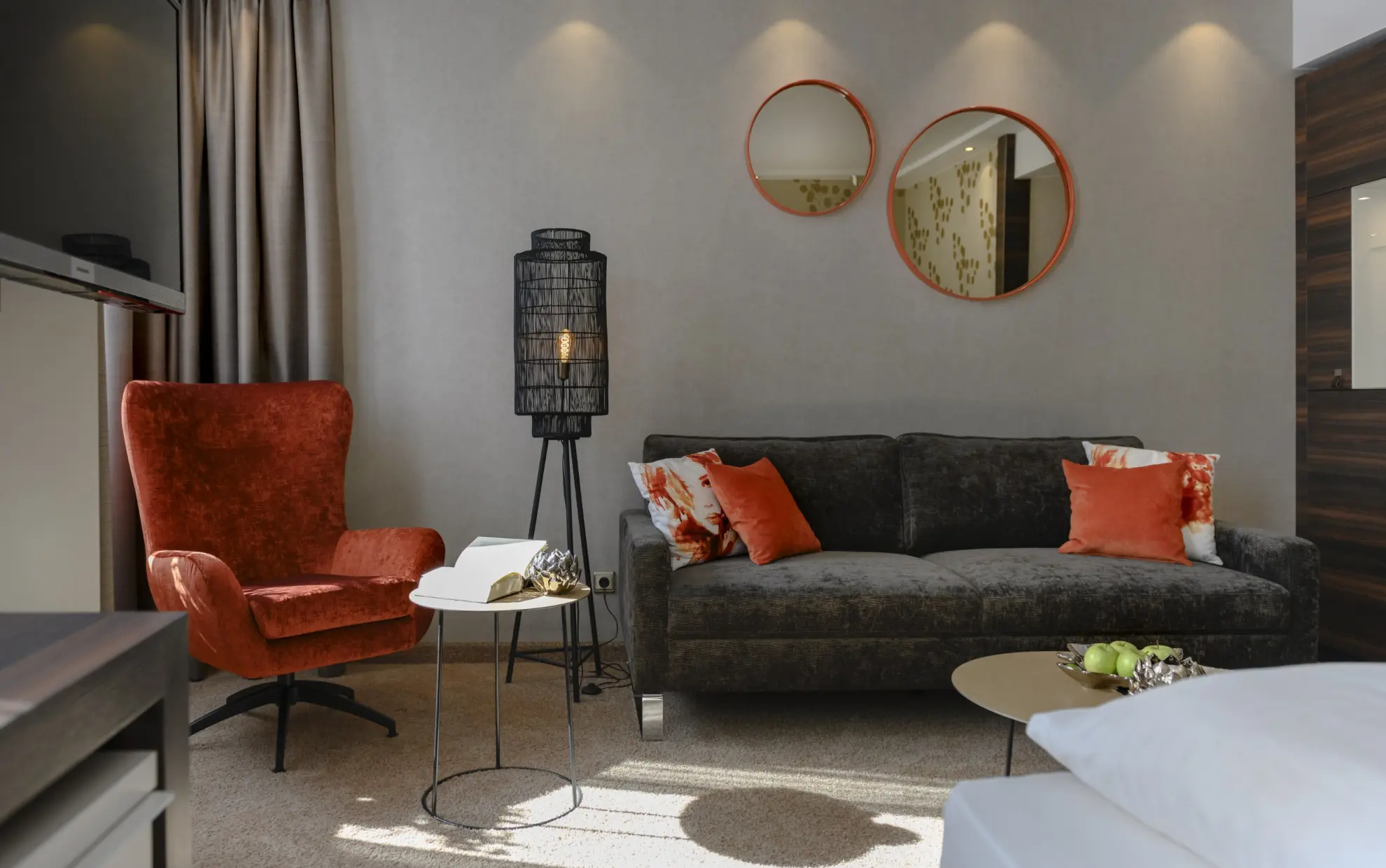 Komfort Plus Doppelzimmer mit Couch Sessel Tisch Stehlampe und runden Spiegelrahmen